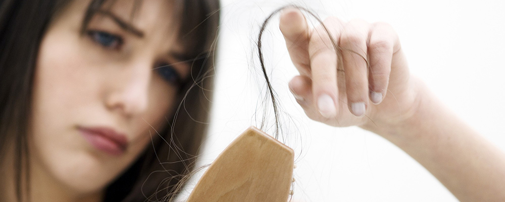 Portrait of a young woman brushing her hair, close up (studio)